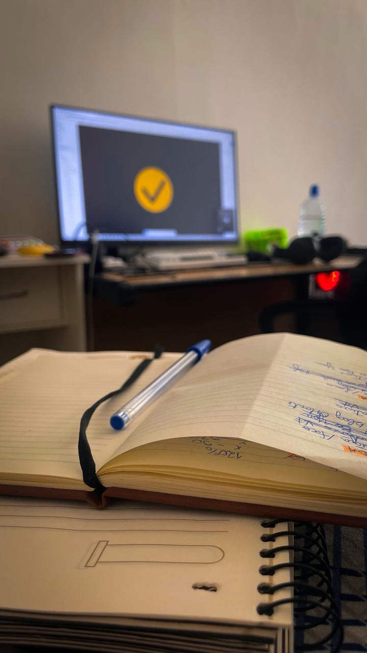 momento de descanso. foto tirada da cama, que mostra meu caderno de tarefas e o computador ligado ao fundo.