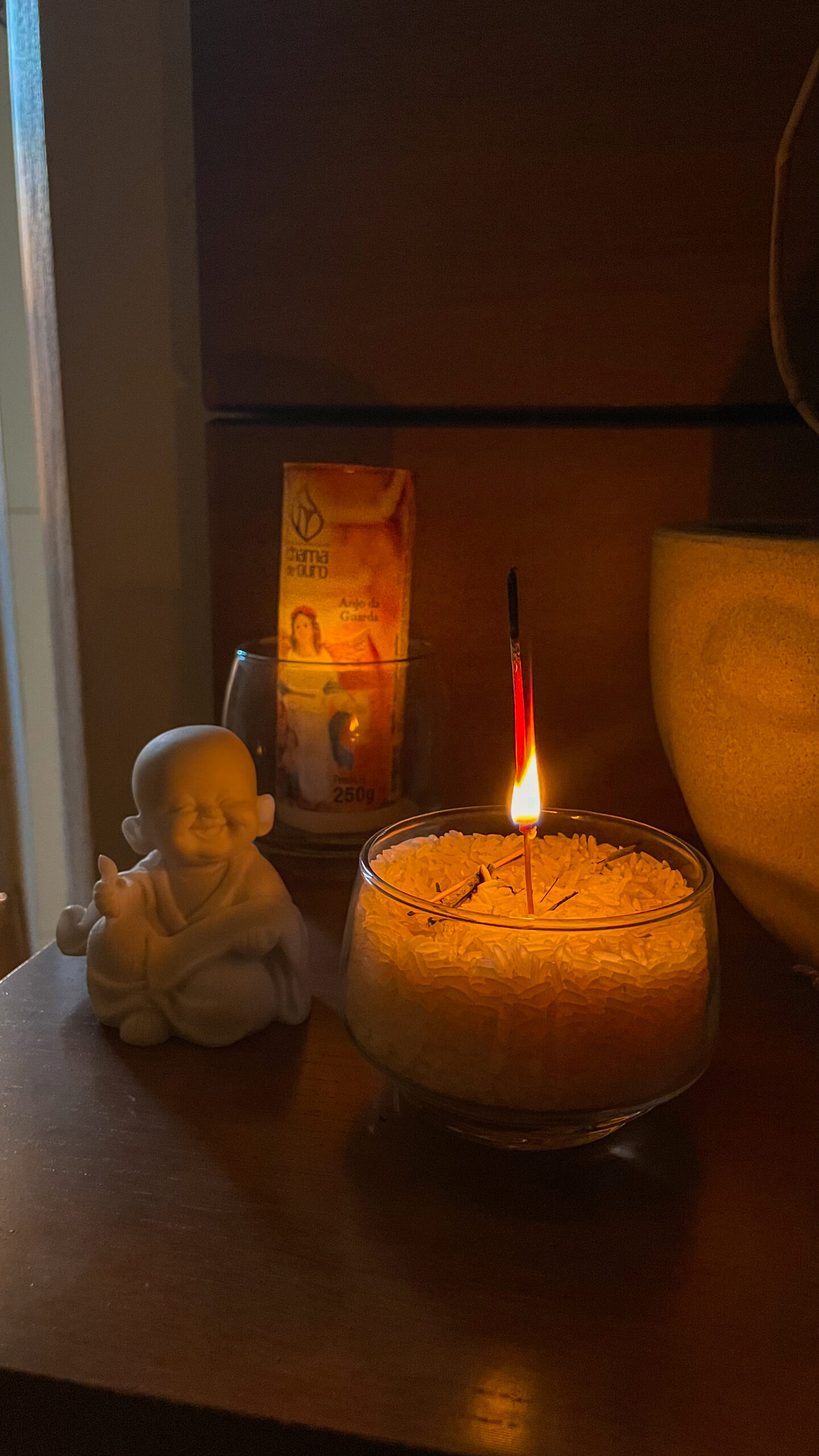 imagem de buda com um incenso aceso ao lado e uma vela acesa ao fundo