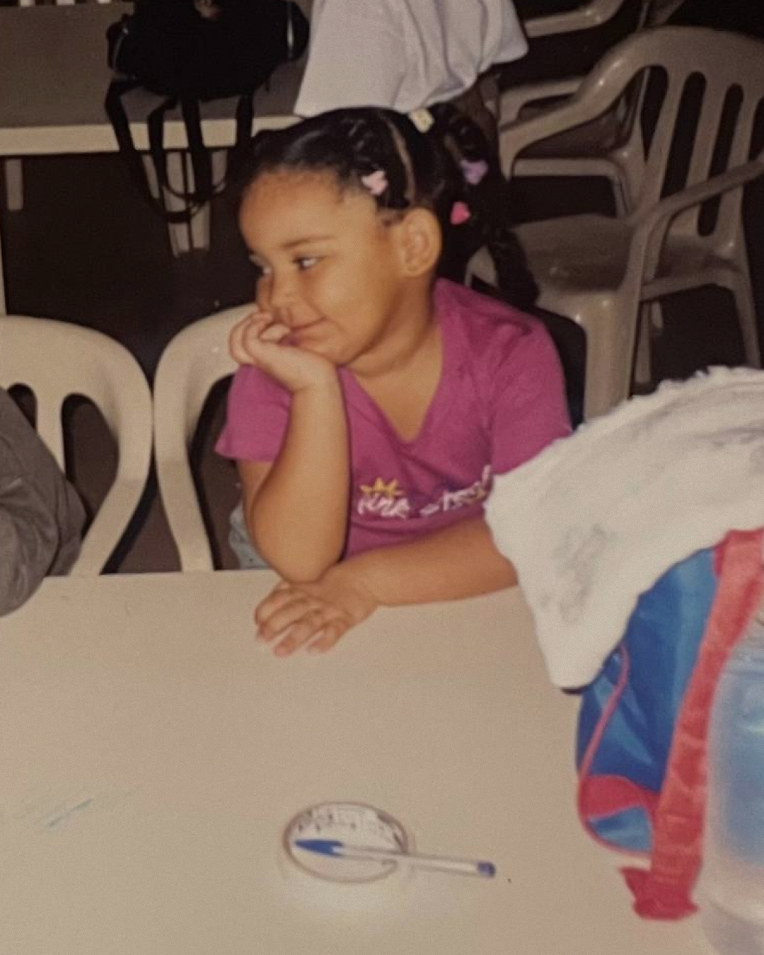 Foto minha, quando criança, olhando para o lado e sorrindo.